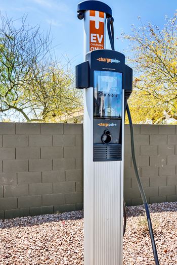 A ChargePoint electric vehicle charging station sits on a gravel area.